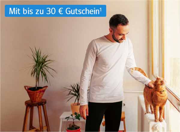 Ein Mann streichelt eine Katze, die auf einer Heizung steht. Im Hintergrund sind die Umrisse eines Wohnzimmers erkennbar.